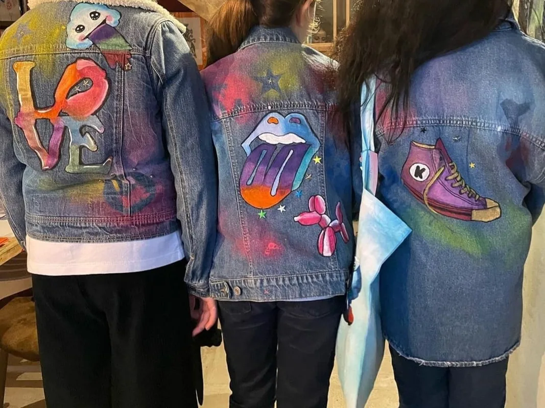Trois vestes en jean customisées, portées de dos : lettrage peint et motifs graphiques